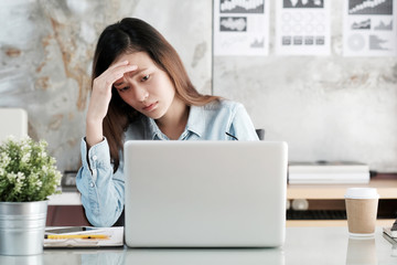Businesswoman looking at laptop computer with stressed face at desk office, business situation,...