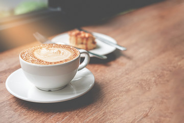 Cup of coffee on wooden table and bakery background in coffee shop