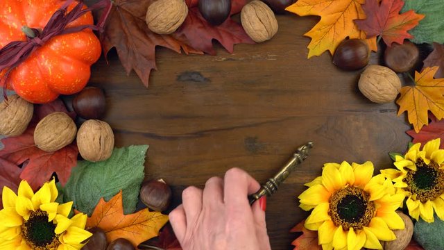 4k Autumn Fall overhead background with decorated borders of leaves and seasonal fruit and nuts on rustic wood table background, real time.