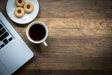 Top view home office table with laptop, coffee and cookie on wooden table. Modern office top view at home. New life style. Concept : business and office.