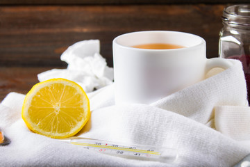 Drugs for colds - pills, spray. Folk remedies - lemon, tea, raspberry jam. Thermometer, handkerchiefs. Treatment of illness, influenza. Warm scarf around the cup.