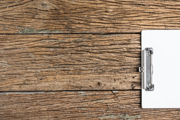 White paper clip board on rough wooden table.