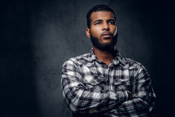 Thoughtful Black male with crossed arms over grey background.