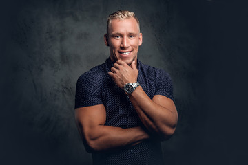 A man posing over grey background in a studio.