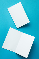 A blank invitation greeting card, a brochure isolated on a turquoise, to replace your design. Vertically.