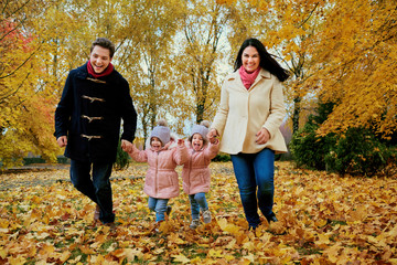 Naklejka na ściany i meble Happy family playing in autumn park.