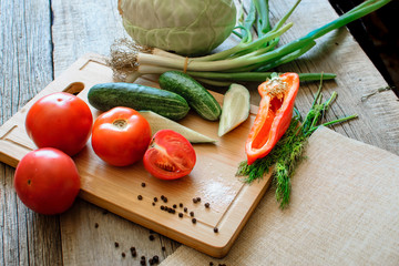 Basket with fresh vegetables (tomatoes, cucumber, chili pepers, dill) on wooden background. Outdoor, in the garden, on the farm. Selective focus, close up. Space for text.