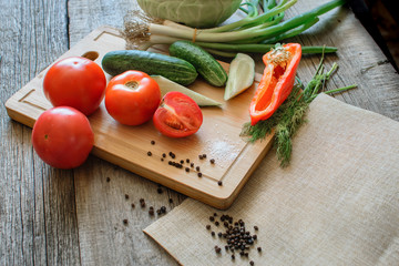 Basket with fresh vegetables (tomatoes, cucumber, chili pepers, dill) on wooden background. Outdoor, in the garden, on the farm. Selective focus, close up. Space for text.