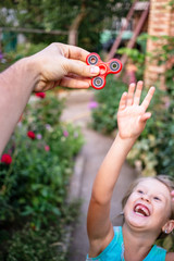 Little girl jumping to the hand with a red spinner