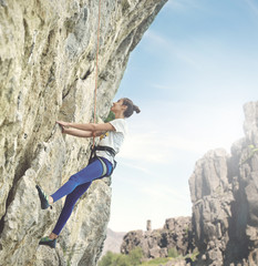 young cheerful woman climbs on the cliff. rock climber Learns to climb rocks on a rocky wall. woman...