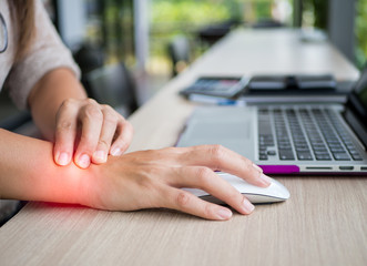 Closeup woman holding her wrist pain from using computer. Office syndrome hand pain by occupational...