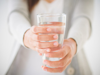 Young woman holding drinking water glass in her hand. Health care concept.