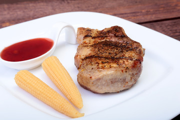 grilled pork chop with Cranberry sauce and Mini Corn cob preserved on plate on wooden board