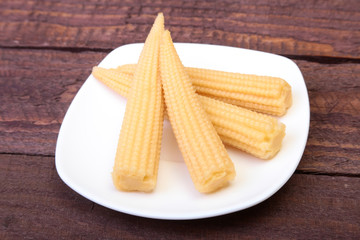Mini Corn cob preserved on plate on wooden board.