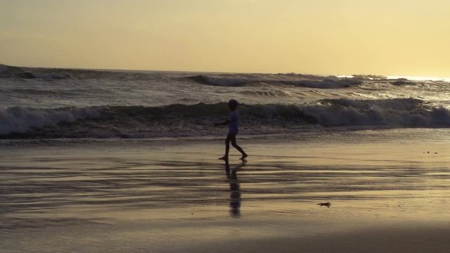 Boy walking on the beach next to the sea, steadycam shot, slow motion shot at 240fps
