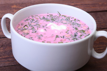 Popular spring cold soup okroshka with yoghurt. Okroshka in a bowl on wooden table. Selective focus