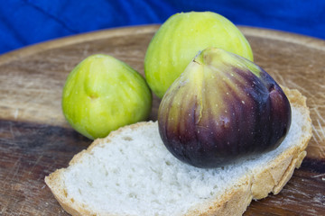fresh tasty figs fruits on a wood plate with a blue background.