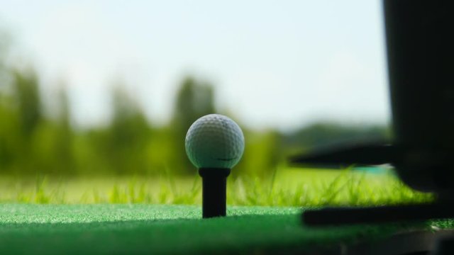 Golf ball behind driver at driving range