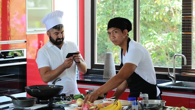 Colleagues at work: Thai and European chefs at the kitchen doing Thai food