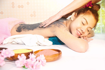 Spa therapist applying scrup salt  and Charcoal on back woman