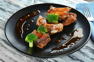 Plate with delicious ribs and broccoli on table