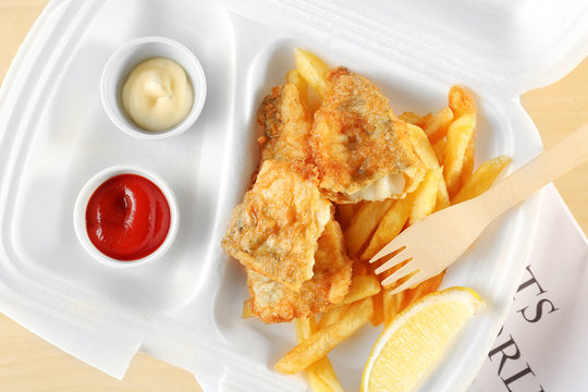 Tasty fried fish and chips with sauce in packaging