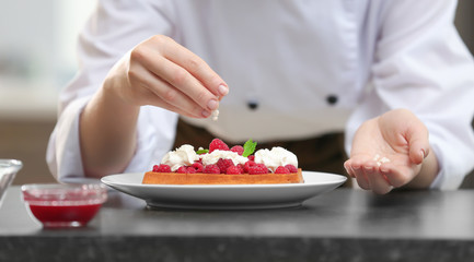 Female chef decorating tasty dessert in kitchen, closeup