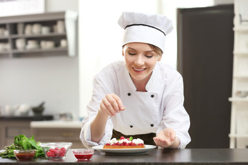 Female chef decorating tasty dessert in kitchen