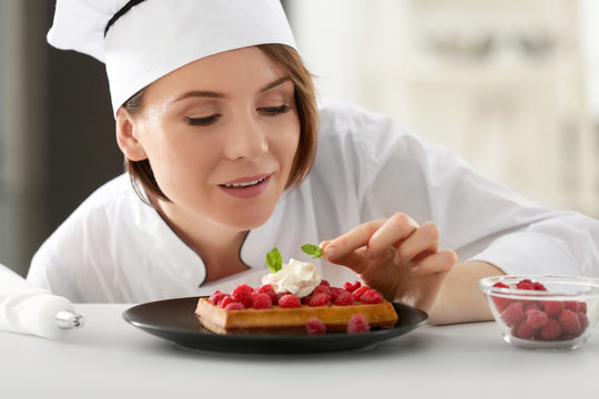 Female chef decorating dessert in kitchen
