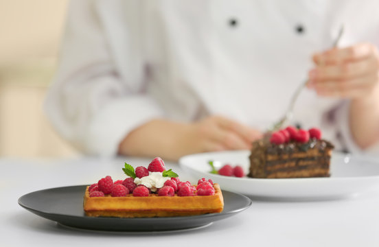 Plate with tasty dessert and blurred chef on background