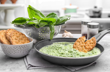 Frying pan with tasty spinach sauce on table