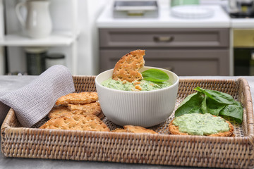 Bowl with tasty spinach sauce on wicker tray