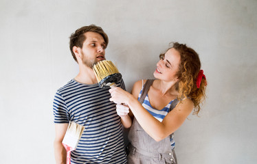 Young couple in love painting walls in their new home.