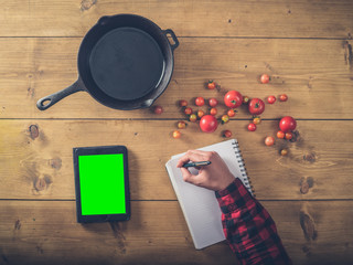 Over view of man writing recipe for fried tomatoes