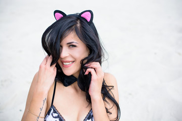 A woman with costume cat's ears and a butterfly around her neck. Playful coquettish girl with a...