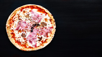 Delicious  Meat Pizza with Ham, Pepperoni and Bacon on a black background.