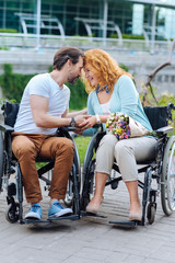 Senior loving couple sitting in the wheelchairs outdoors