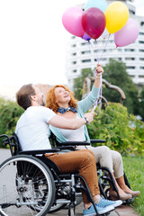 Cheerful senior disabled couple holding balloons