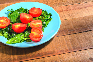 Tomatoes and greens spinach on a blue plate