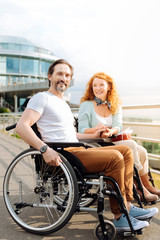 Fototapeta na wymiar Cheerful disabled man resting outdoors with his loving wife