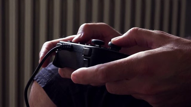 Man playing video game with joypad, close up of male hands with gaming equipment