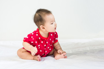 Portrait of adorable baby sitting on a white floor and smiling with copyspace