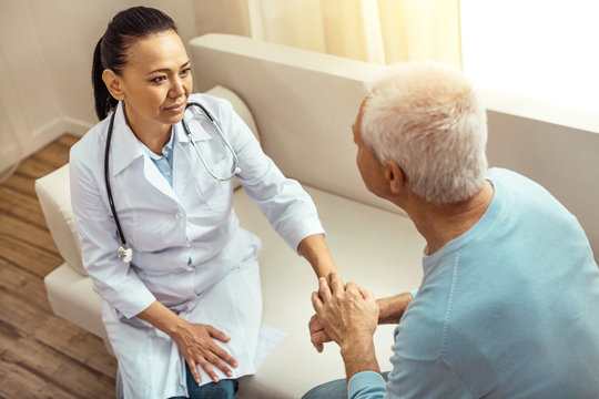 Nice elderly patient holding his nurses hand