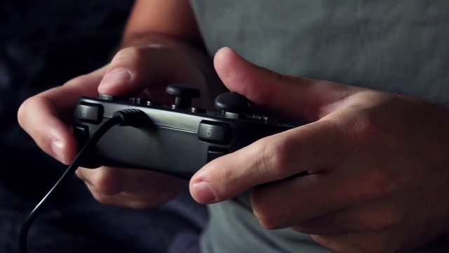 Man playing video game with joypad, close up of male hands with gaming equipment