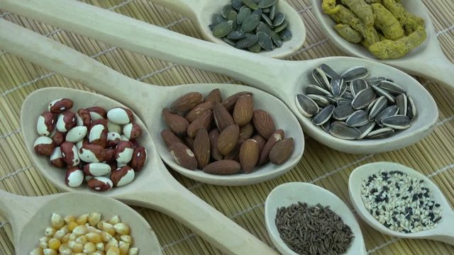 Rotating group wooden spoons with various vegetables, spice and nuts, food background