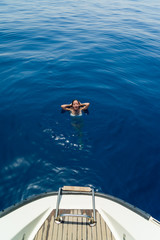 Fototapeta na wymiar Young woman swimming by the sailing boat