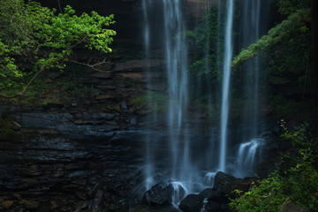Fototapeta na wymiar Waterfall impact on black stone at the jungle