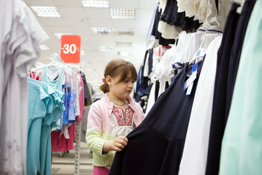 little girl choosing clothes for  school in  store