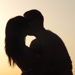 Young couple kissing on the beach, at sunset