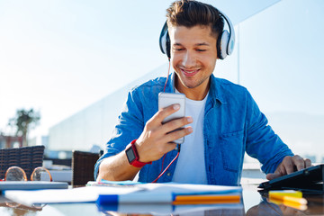 Radiant guy using smartphone while listening to music